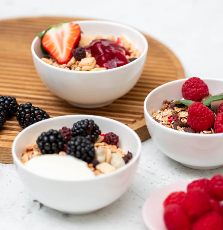 article1a-muesli-celebration-minis.jpg Drei Mueslischalen mit Muesli und frischen Beeren